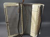 an old white accordion sitting on top of a table next to a black wall