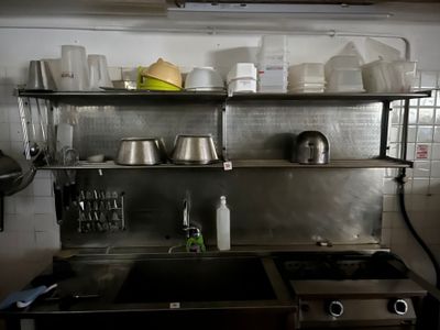 une cuisine équipée d'une cuisinière, d'un évier et de casseroles et poêles rangées sur les étagères