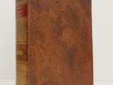 an old book with a brown cover sitting on top of a white table