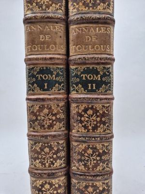 two old books sitting on top of each other on a table