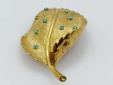 a gold leaf brooch with turquoise stones on it