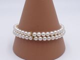 bracelet de perles avec un fermoir doré sur un cône à fond blanc
