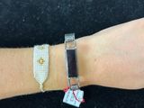 a woman ' s hand with a bracelet that has a tag attached to it