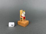 a small white dog sitting on a chair next to a small white clock