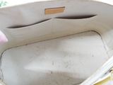 a person holding a white purse with a wooden handle