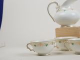 three cups and a pitcher sitting on a table