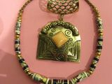 necklace with a gold pendant with a yellow stone on a pink background