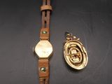an image of a gold watch and a gold charm on a black surface