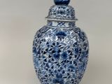 un vase bleu et blanc surmonté d'un oiseau