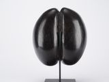 a black sculpture of an egg on a black stand