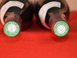 two bottles of wine sitting on a red cloth