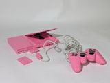 une console de jeux vidéo rose avec deux manettes et un chargeur