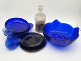 un bol en verre bleu, une assiette bleue et un bol noir posés sur une surface blanche