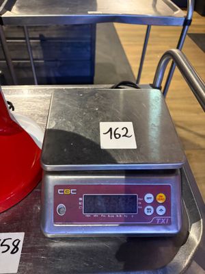 une bouilloire rouge posée sur une balance, sur une table