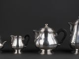 a group of five silver teapots and a coffee pot