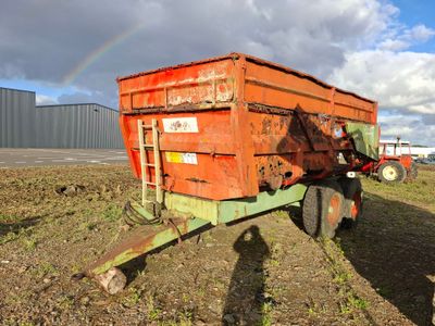 a red dump truck parked in a field with a rainbow in the sky