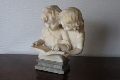 a statue of two children reading a book on a table