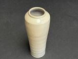 a white vase sitting on a table with a black background