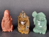 three small figurines of different colors sitting on a black surface