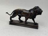 statue en bronze représentant un lion, posée sur un socle en marbre, sur fond blanc