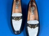 pair of black and white shoes with a gold buckle on the front