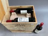 two bottles of wine in a wooden box next to a bottle of wine