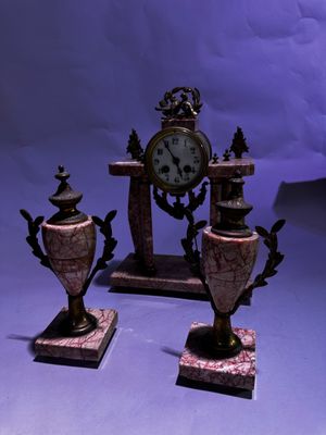 trois vases posés à côté d'une horloge sur une table