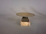 a silver plate on a marble base on a gray background
