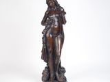 une statue antique en bronze représentant une femme tenant un sac