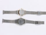 two watches are shown on a white surface, one is silver and the other is gold