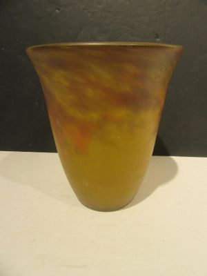 a yellow vase sitting on a table with a black wall behind it