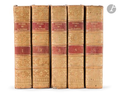 four old books are lined up in a row on a white surface