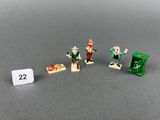 three miniature figurines of a man and a woman with guns and a green box