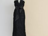 une robe noire posée sur un mannequin adossé à un mur