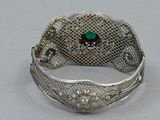 silver bracelet with a green stone in the middle of it