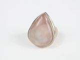 gros plan d'une bague en pierre rose sur une surface blanche