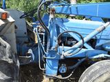 a blue tractor that is parked in the grass
