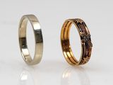 two gold and silver wedding rings on a white surface