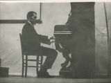 photographie en noir et blanc d'un homme assis au piano