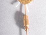 une pièce d'or posée sur un cure-dent, sur une surface blanche