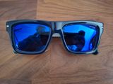 Quelqu'un prend une photo d'une paire de lunettes de soleil posée sur une table en bois.