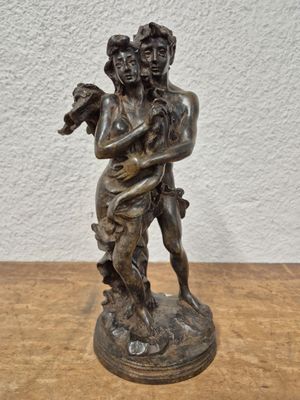 statue en bronze représentant une femme tenant un enfant, posée sur une table en bois