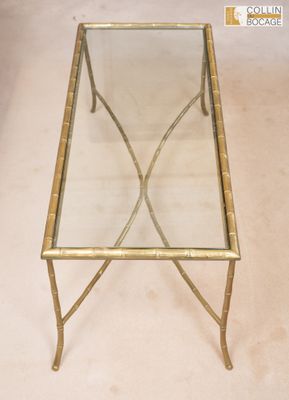 une table basse en verre avec une structure en métal doré et un plateau en verre