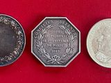 trois pièces d'argent posées les unes à côté des autres sur une surface rouge