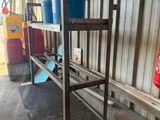 a metal shelf with two buckets on it in front of a building
