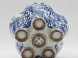 blue and white vase with four holes in it on a white surface