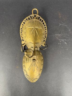 un vieux masque en laiton accroché au mur