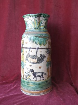 a vase with a picture of animals on it on a red cloth