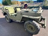 une jeep verte garée sur un parking près d'une clôture