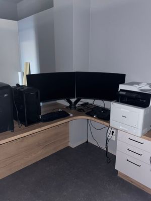 a computer desk with two monitors and a printer on it